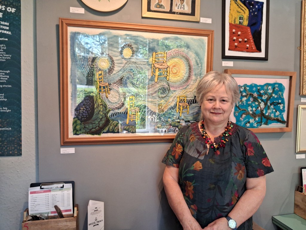 Jill Powell by the side of her picture in Llantarnum Grange cafe